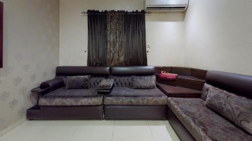 a leather couch in a room with a curtain at شاطئ البساتين للشقق المخدومة in Jeddah
