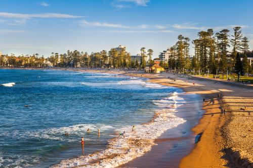 a beach with people walking on the sand and water at Lotus Stay Manly - Apartment 29B in Sydney