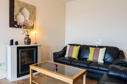 a living room with a black leather couch and a fireplace at The Courtyard Apartments in Carrick on Shannon