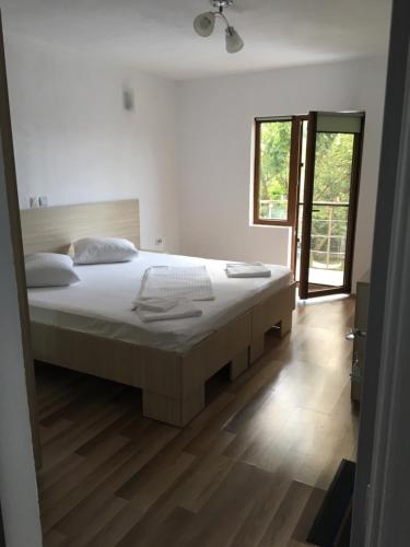 a white bedroom with a large bed and a window at Vila Angi in Mangalia