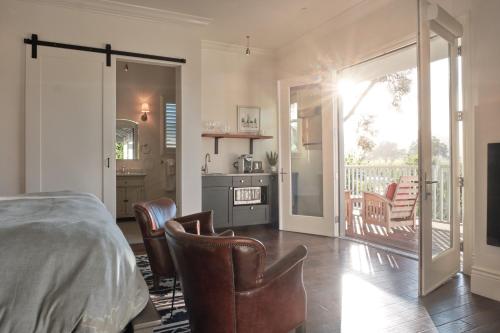 a bedroom with a bed and chairs and a balcony at The Setting Inn Napa Valley in Napa