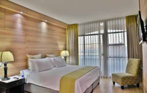 a bedroom with a large bed and a chair at The Capetonian - Halal in Cape Town