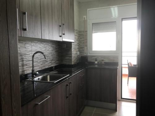 a kitchen with wooden cabinets and a sink and a window at Star of the Sea Miami Playa vacaciones frente al Mar in Miami Platja