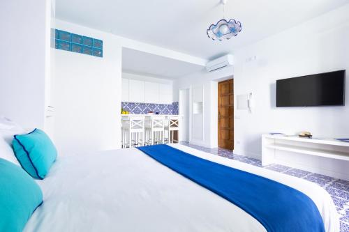 una camera da letto con un grande letto bianco con cuscini blu di Blue View Capri Apartment a Capri