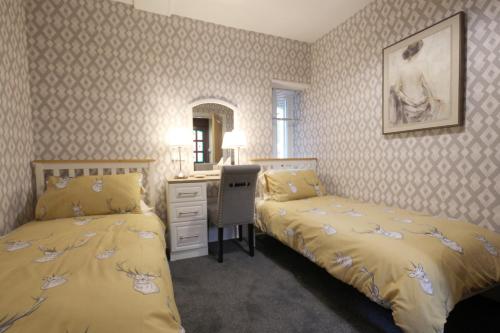 a bedroom with two beds and a desk and a mirror at Arrandale in Inverness