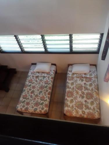two beds in a room with a window at La Sagesse Hotel, Restaurant and Beach Bar in Content