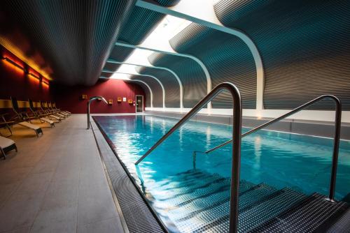 a large indoor swimming pool with escalators in a building at Mirabeau Alpine in Zermatt