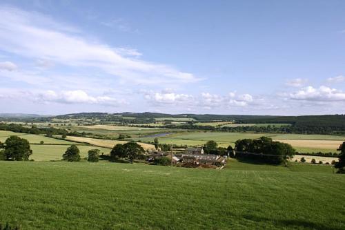 um grande campo verde com uma casa no meio em Anick Grange Farm B&B em Hexham