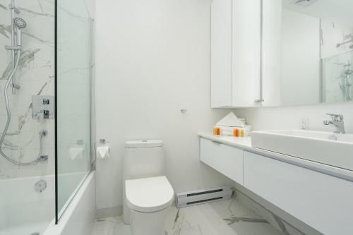 a white bathroom with a toilet and a sink at Le Se7t Penthouses in Montréal