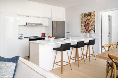 a kitchen with white cabinets and black bar stools at Le Se7t Penthouses in Montréal