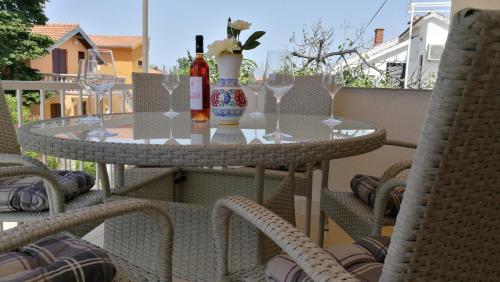 a table with wine glasses and a vase on a balcony at Apartments KUS Ugljan in Ugljan