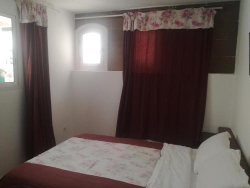 a bedroom with a bed with red curtains and a window at Miramar in El Harhoura