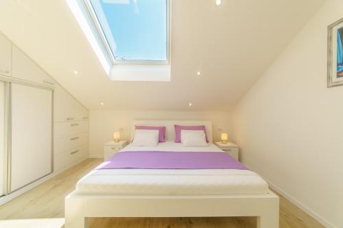 Cette chambre comprend un lit avec des draps violets et une lucarne. dans l'établissement Dalmat Apartment, à Split