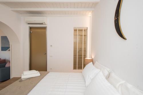 a white bedroom with a bed and a window at Levantes House Mykonos in Ano Mera