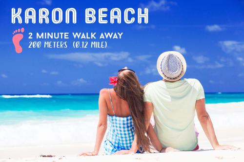 a man and a woman sitting on the beach at Phoenix Hotel Karon Beach in Karon Beach