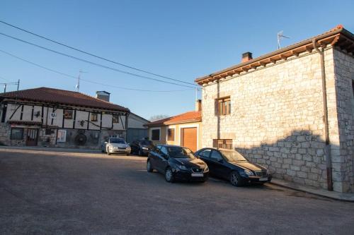 dois carros estacionados num parque de estacionamento ao lado de um edifício em Casa rural Los Bodones em Quintanilla Riopico