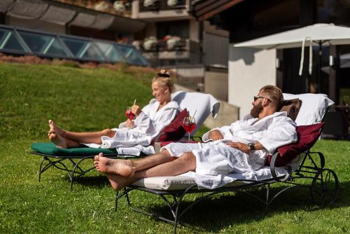 three people sitting on lawn chairs in the grass at Mirabeau Alpine in Zermatt