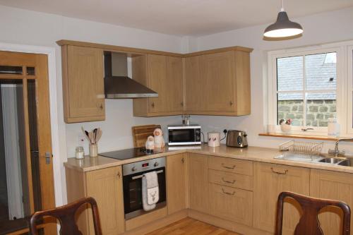a kitchen with wooden cabinets and a stove top oven at Roualeyn in Huntly