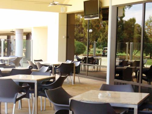 an empty restaurant with tables and chairs and windows at Rich River Golf Club in Moama