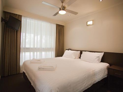 a bedroom with a white bed with two towels on it at Rich River Golf Club in Moama