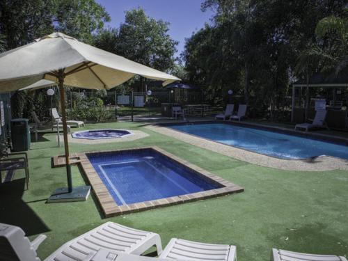 a patio area with a pool and lawn chairs at Rich River Golf Club Resort in Moama