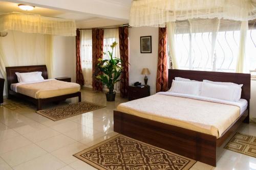 a bedroom with two beds and two windows at Reinah Tourist Hotel Fort Portal in Fort Portal