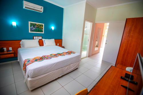 1 dormitorio con 1 cama grande y pared azul en Brisamar Hotel Pousada en Barra de São Miguel