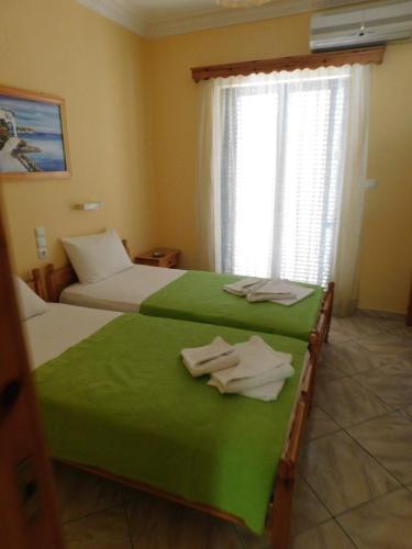 a bedroom with two beds with green sheets and a window at To Spiti Tis Eirinis in Poros