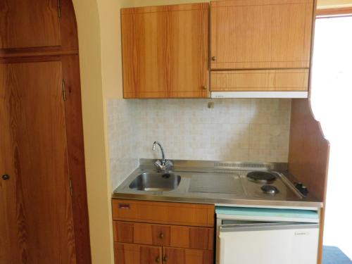 a small kitchen with a sink and wooden cabinets at To Spiti Tis Eirinis in Poros
