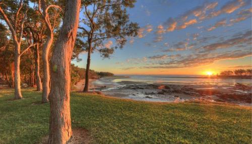 a view of a beach with trees and a sunset at Discovery Parks - Tannum Sands in Tannum Sands