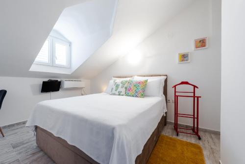 a bedroom with a white bed with a red shelf at Apartments Grgich in Dubrovnik
