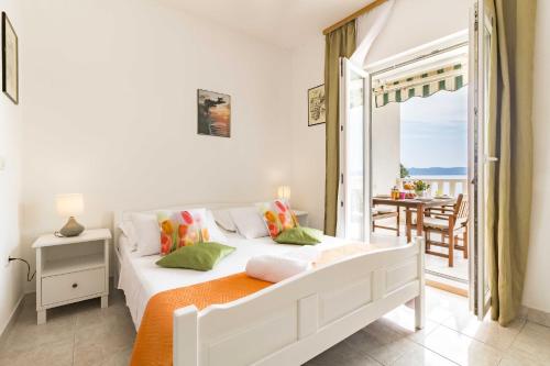 - une chambre blanche avec un lit et un balcon dans l'établissement Villa Smokvina, à Bogomolje