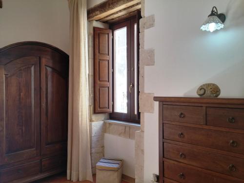 una camera da letto con cassettiera in legno e finestra di La Casetta di Apollo a Siracusa