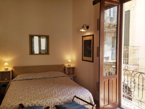 una camera con letto e balcone di La Casetta di Apollo a Siracusa
