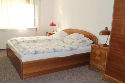 a bedroom with a wooden bed with white sheets and pillows at Evelin Nyaralóház in Siófok