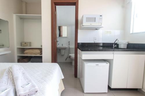 una pequeña cocina blanca con cama y lavabo en Ilha Norte Apart Hotel, en Florianópolis