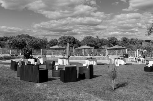 a group of tables with chairs and umbrellas in a field at Cidadelhe Rupestre Turismo Rural in Cidadelhe