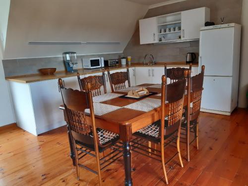 a kitchen with a wooden table with chairs and a white refrigerator at Vlei Lofts in Cape Town