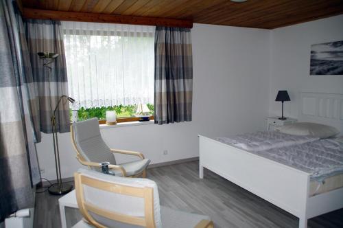 ein Schlafzimmer mit einem Bett, einem Stuhl und einem Fenster in der Unterkunft Bungalow am Forsthaus Stagnieß in Ückeritz