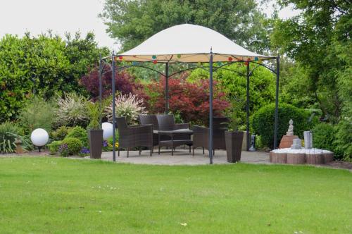 a gazebo with chairs under it in a garden at Ferienwohnung Sonne & Sauna in Sönnebüll