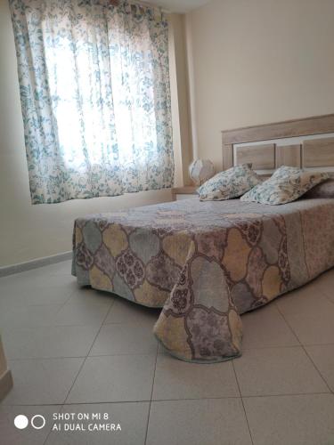 1 dormitorio con cama y ventana en ApartaClub la Barrosa, en Chiclana de la Frontera