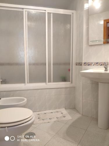 a bathroom with a toilet and a sink and a window at ApartaClub la Barrosa in Chiclana de la Frontera