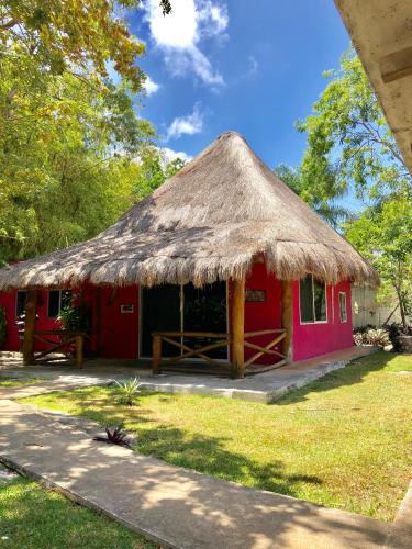 坎昆的住宿－Ch'ejum bungalow，一座红色的小建筑,拥有茅草屋顶