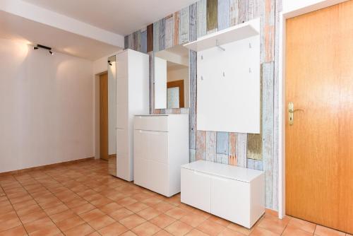 a kitchen with white cabinets and a tile wall at Haus Hafeneck mit Frühstücksoption in Bensersiel