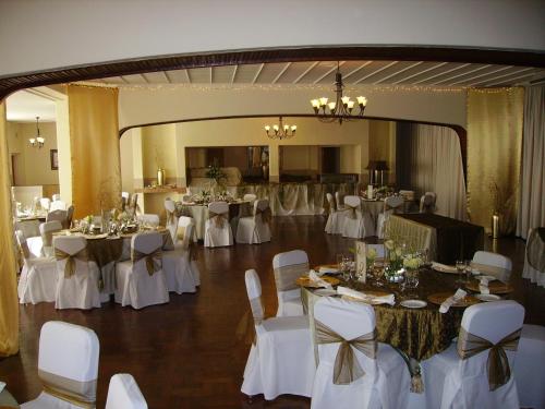un salón de banquetes con mesas blancas y sillas blancas en The Shakespeare Inn en Vanderbijlpark