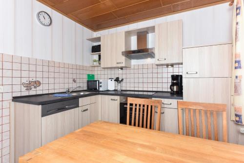 a kitchen with white cabinets and a wooden table at Haus Hafeneck mit Frühstücksoption in Bensersiel