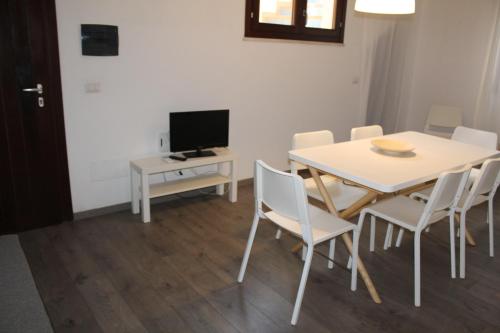 una sala da pranzo con tavolo, sedie e televisione di Boa Vista Favignana - Home&Beach a Favignana