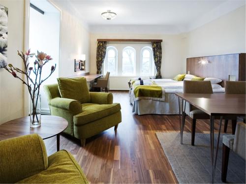 duży pokój hotelowy z łóżkiem i krzesłami w obiekcie Grand Hotel Alingsås w mieście Alingsås