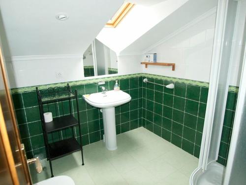 Baño de azulejos verdes con lavabo y espejo en Apartamentos Rurales Casa Tata, en Villaviciosa