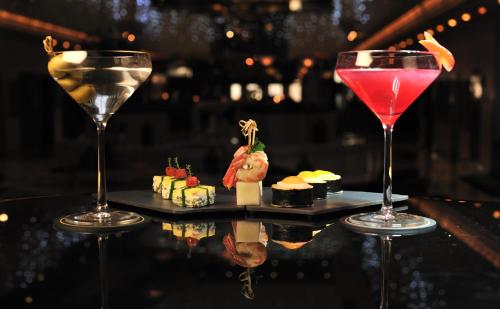 two wine glasses sitting on top of a table with sushi at Sofitel Algiers Hamma Garden in Alger